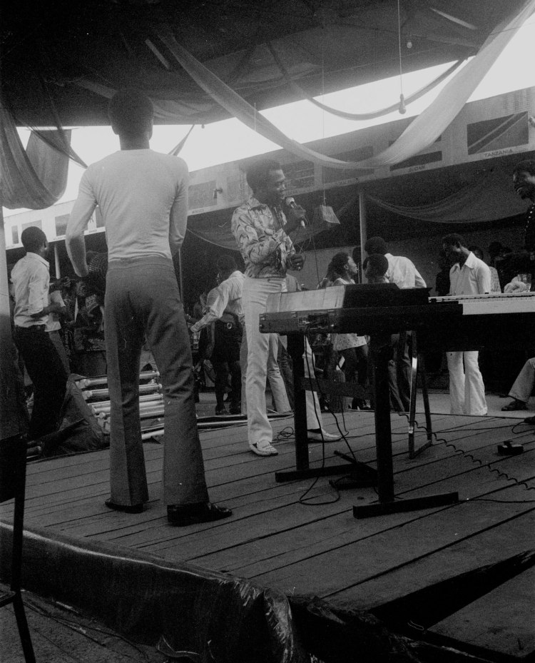 fela kuti singing into microphone on stage at the shrine in lagos nigeria 1978 with his band around him