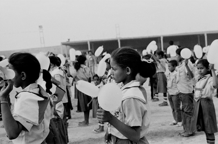 girl in thought among children in uniform holding white balloons at polisario ten year celebration western sahara 1986