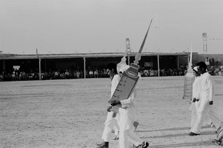 men and women marching in white medical uniforms with syringe cut outs polisario ten year celebration western sahara 1986