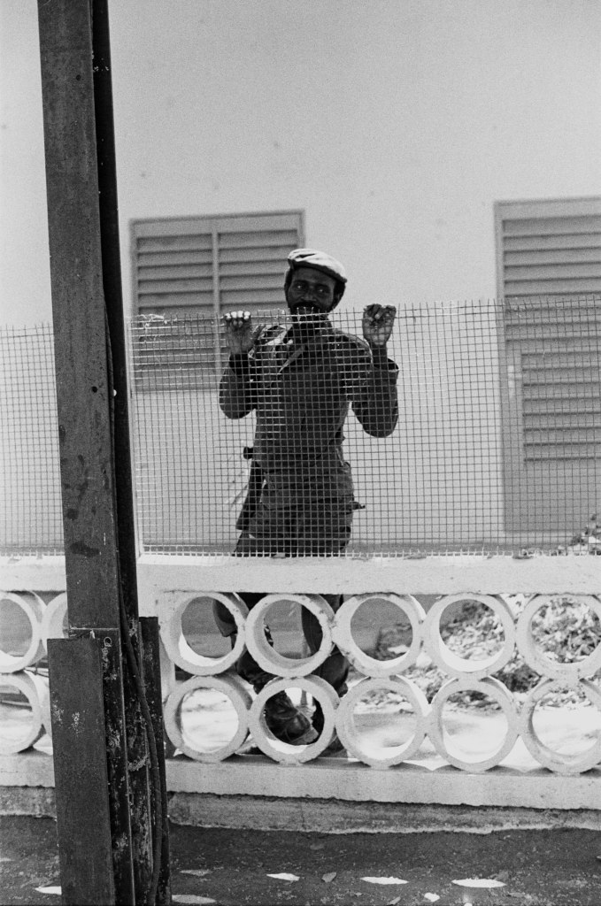 soldier wearing beret smiles behind a fence