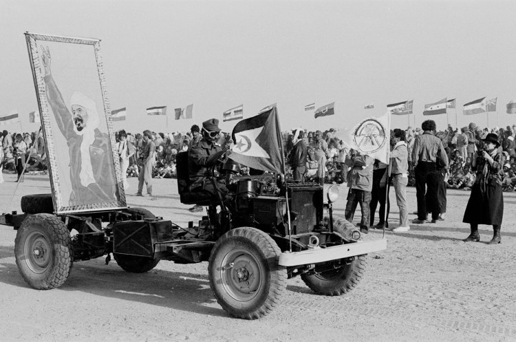 tractor with driver wearing sunglasses and large framed iconic picture on the back polisario ten year celebration western sahara 1986